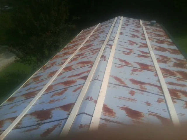 Rusted metal roof panels with new wood purlins before replacement — Storm Damage Roof Repair in Lane by Roofing Brothers