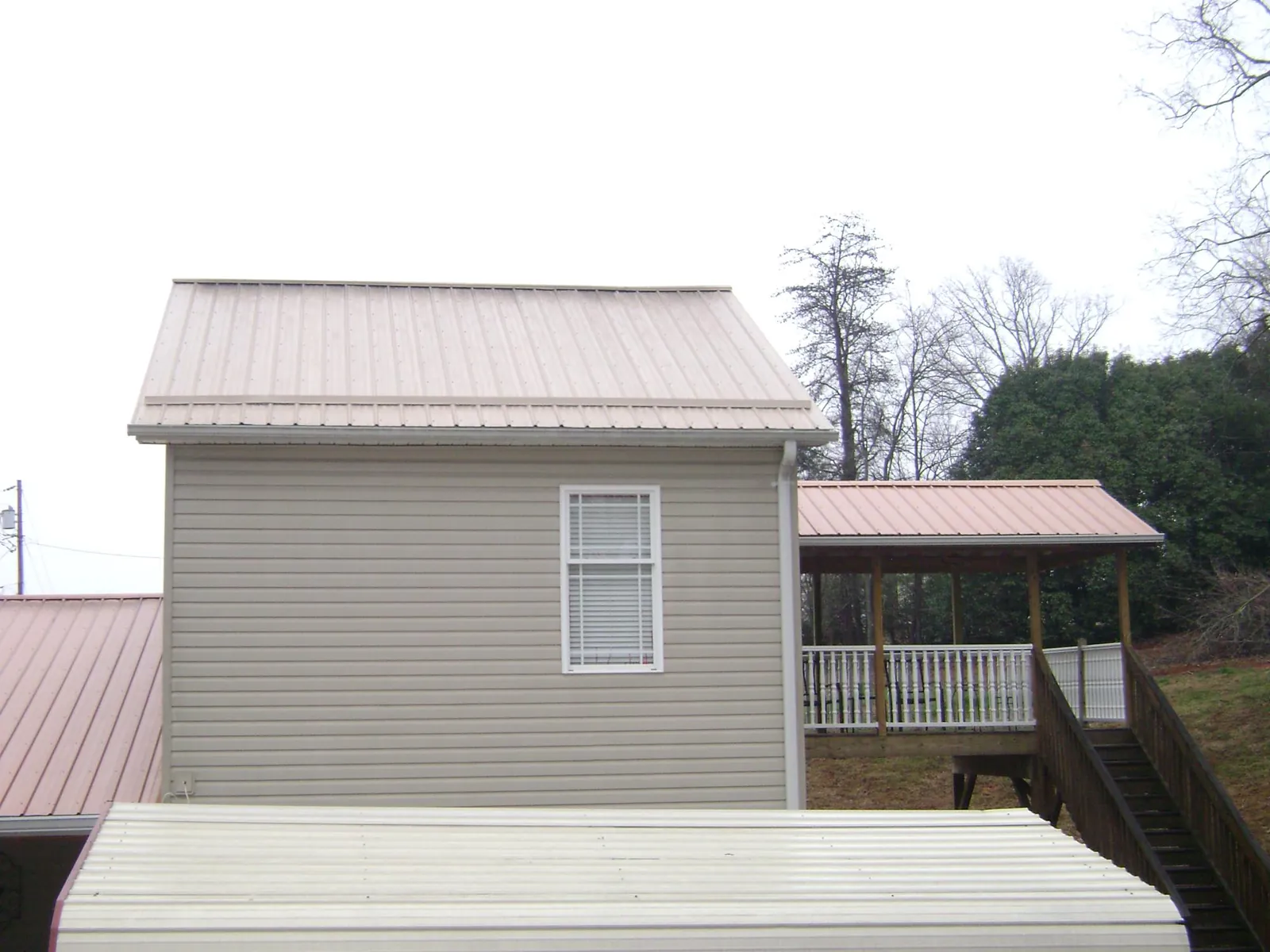 Tan metal roofs on a two story addition and attached porch, from a Roof Replacement job in Lane