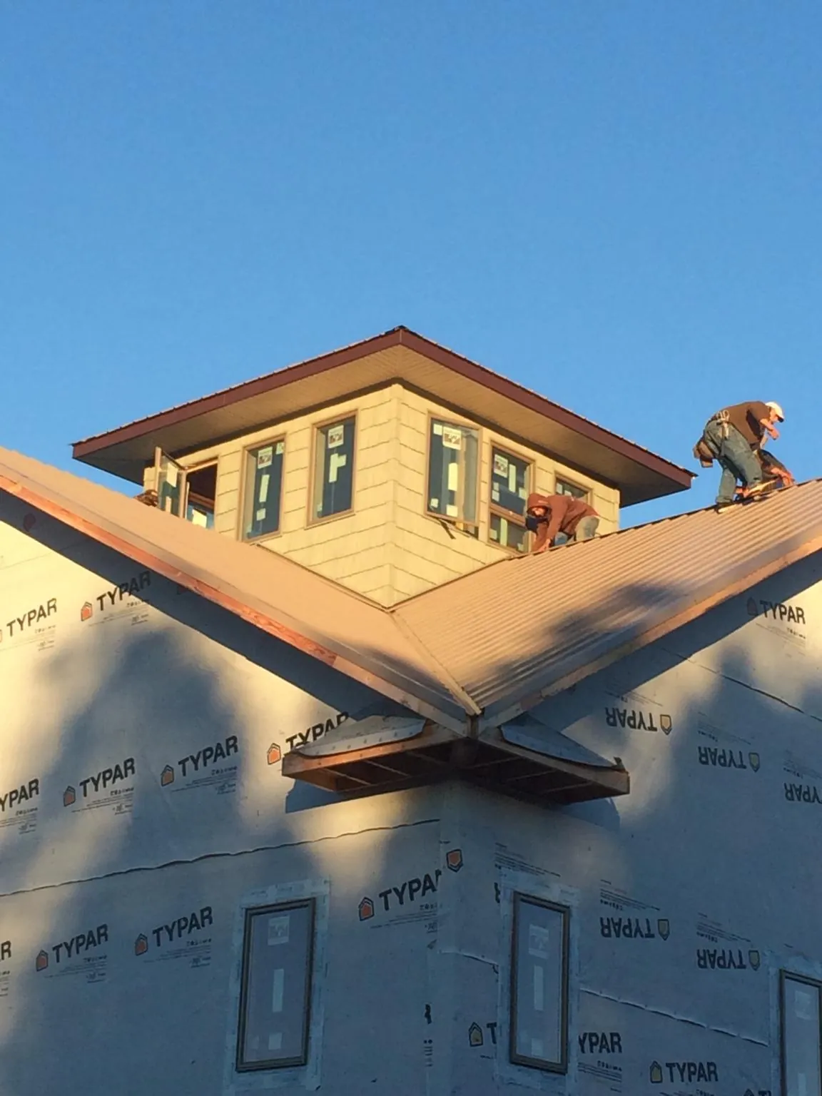 Roofers working around a rooftop cupola on a new metal roof at sunset — Roof Waterproofing in Lane by Roofing Brothers